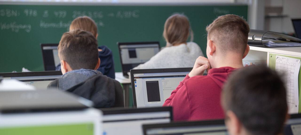 Beschreibung Schülerinnen und Schüler nehmen im Klassenzimmer einer 9. Klasse der Gemeinschaftsschule Leutenbach am Geografieunterricht mit Hilfe von Laptops und Tablets teil.