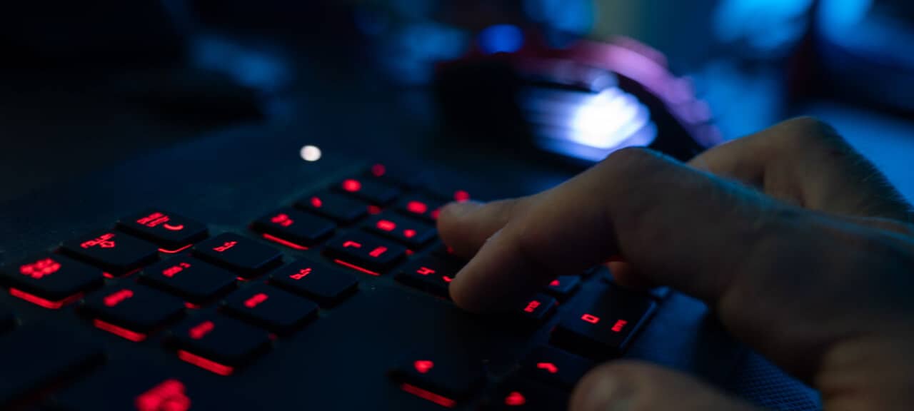 Ein Mann sitzt am Rechner und tippt auf einer Tastatur.