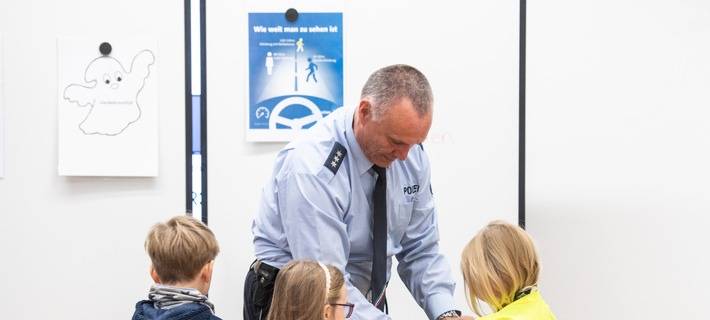 Polizeihauptkommissar Holger Siegburg erklärt den Erstklässlern der Pinguinklasse, warum helle, reflektierende Kleidung so wichtig ist.