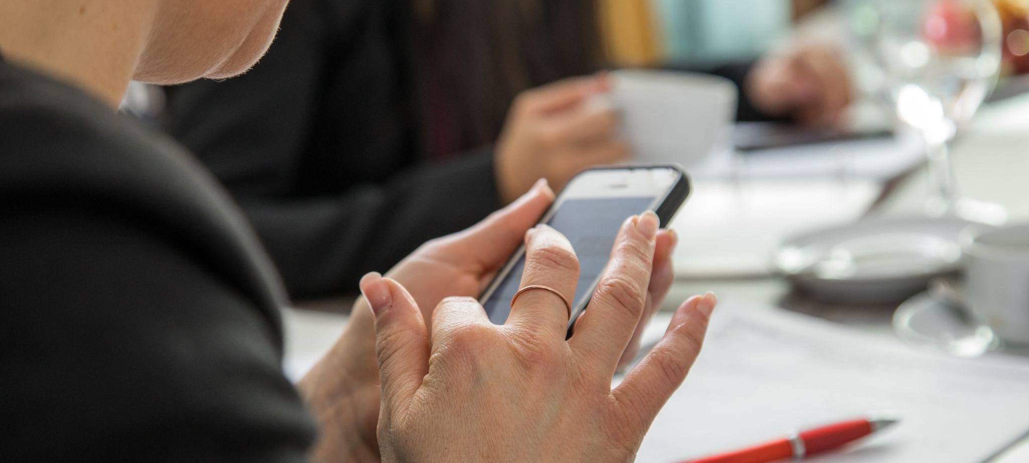 Eine Frau mit Smartphone am Arbeitsplatz