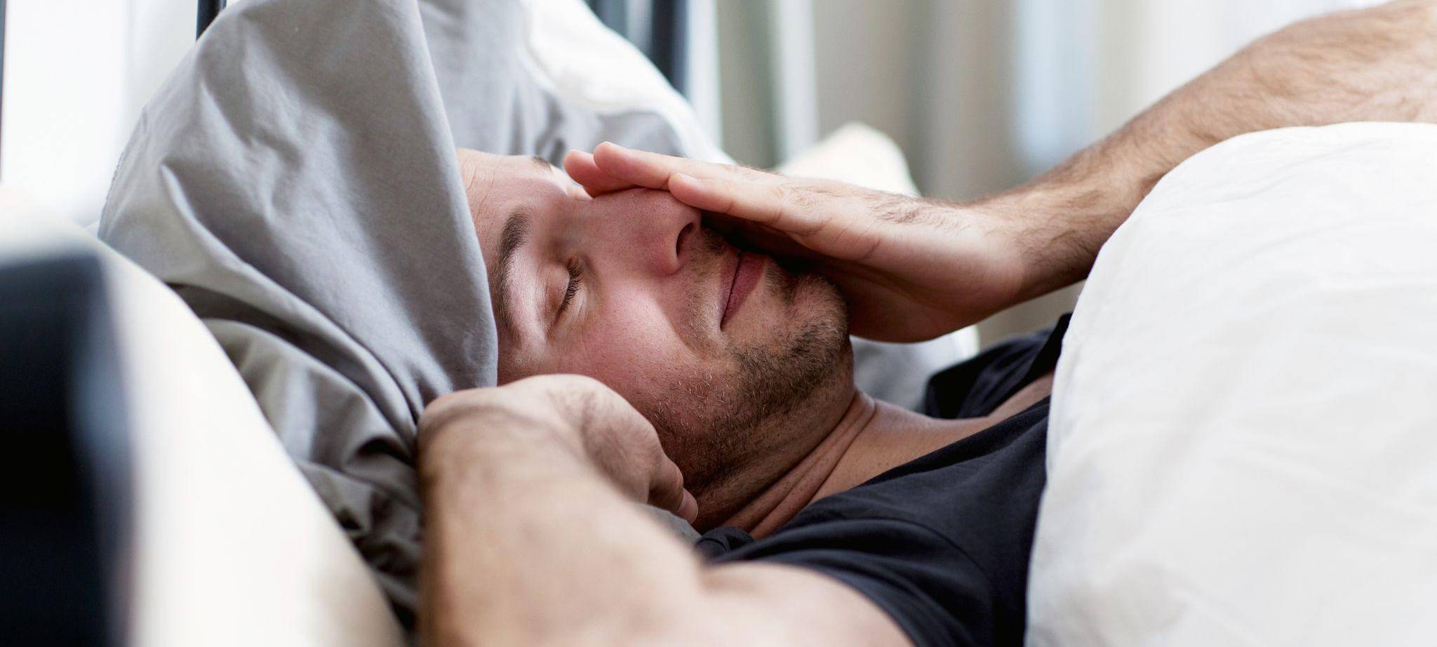 Ein Mann liegt verschlafen im Bett