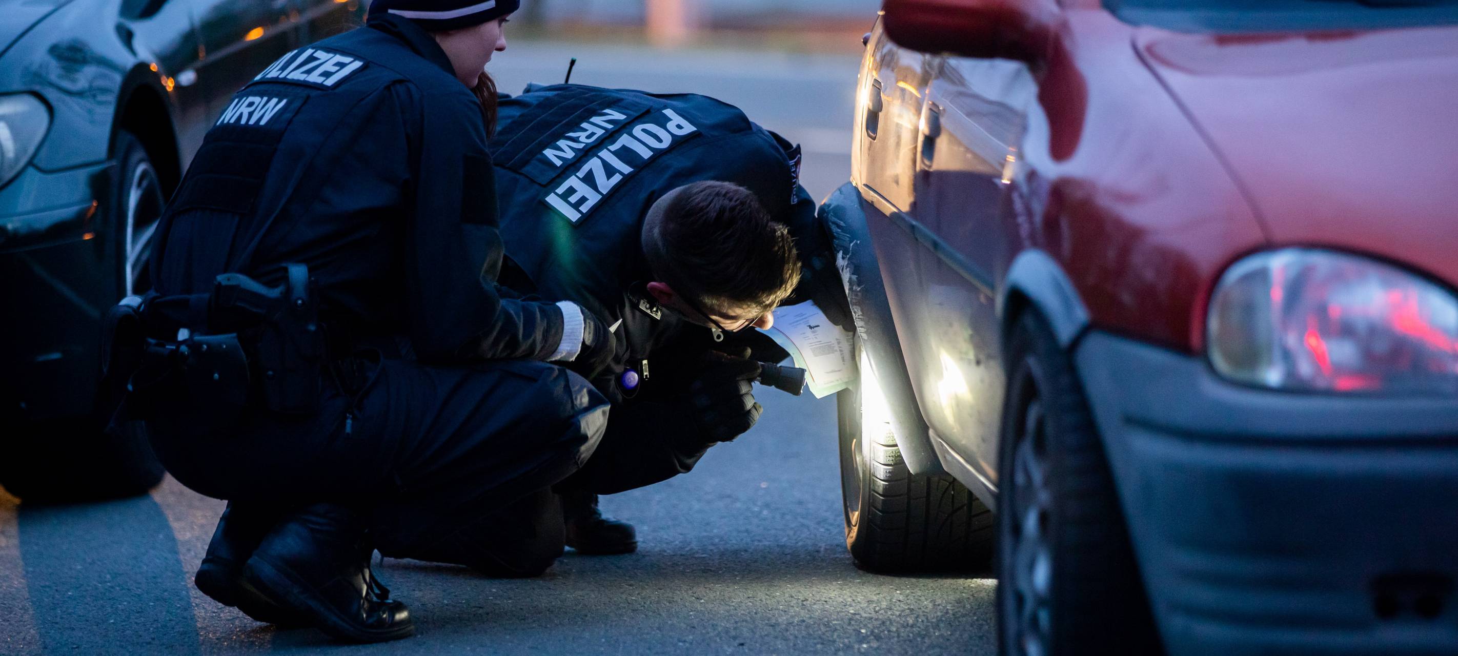 Zwei Polizeibeamte kontrollieren ein getuntes Auto