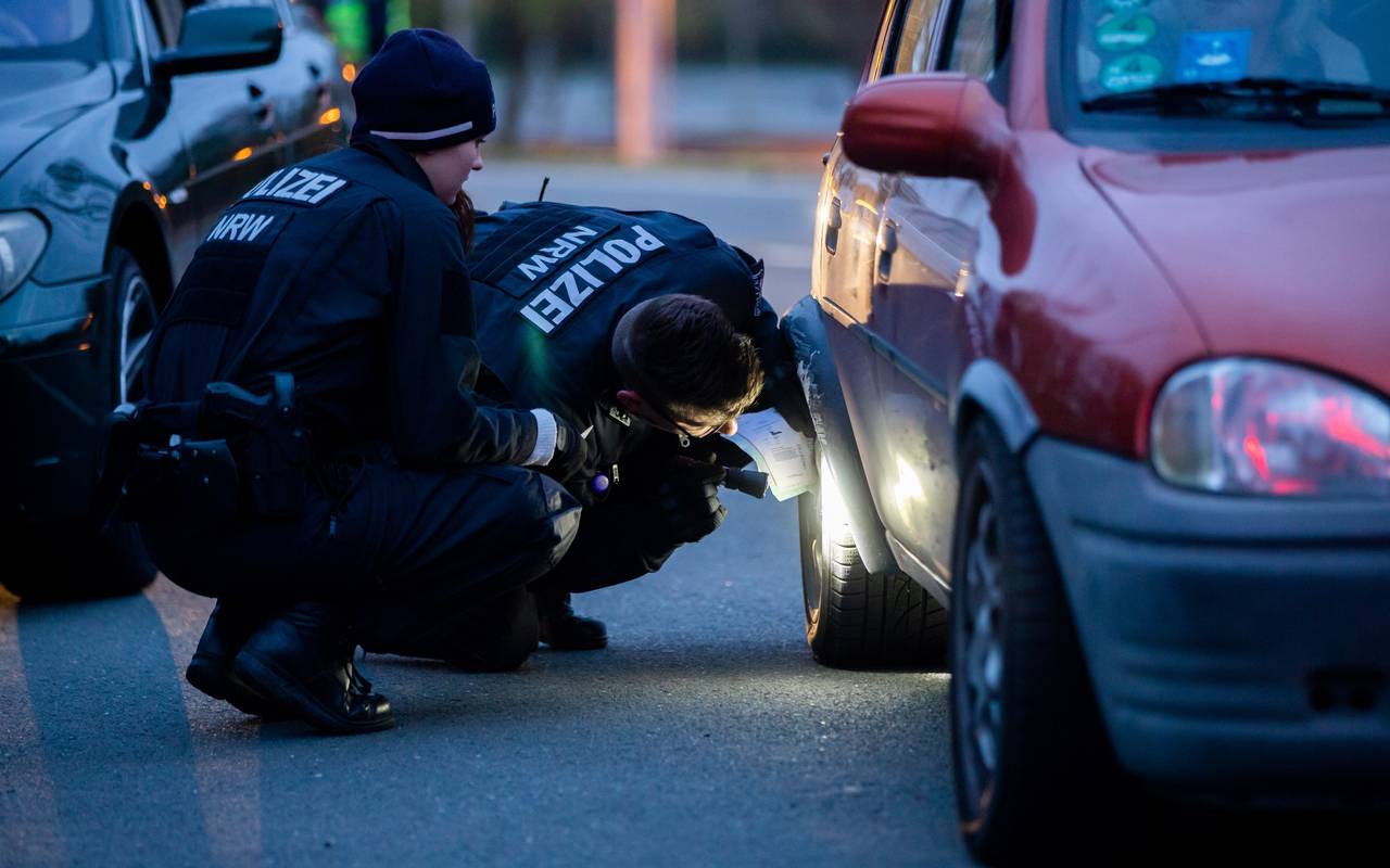 Zwei Polizeibeamte kontrollieren ein getuntes Auto