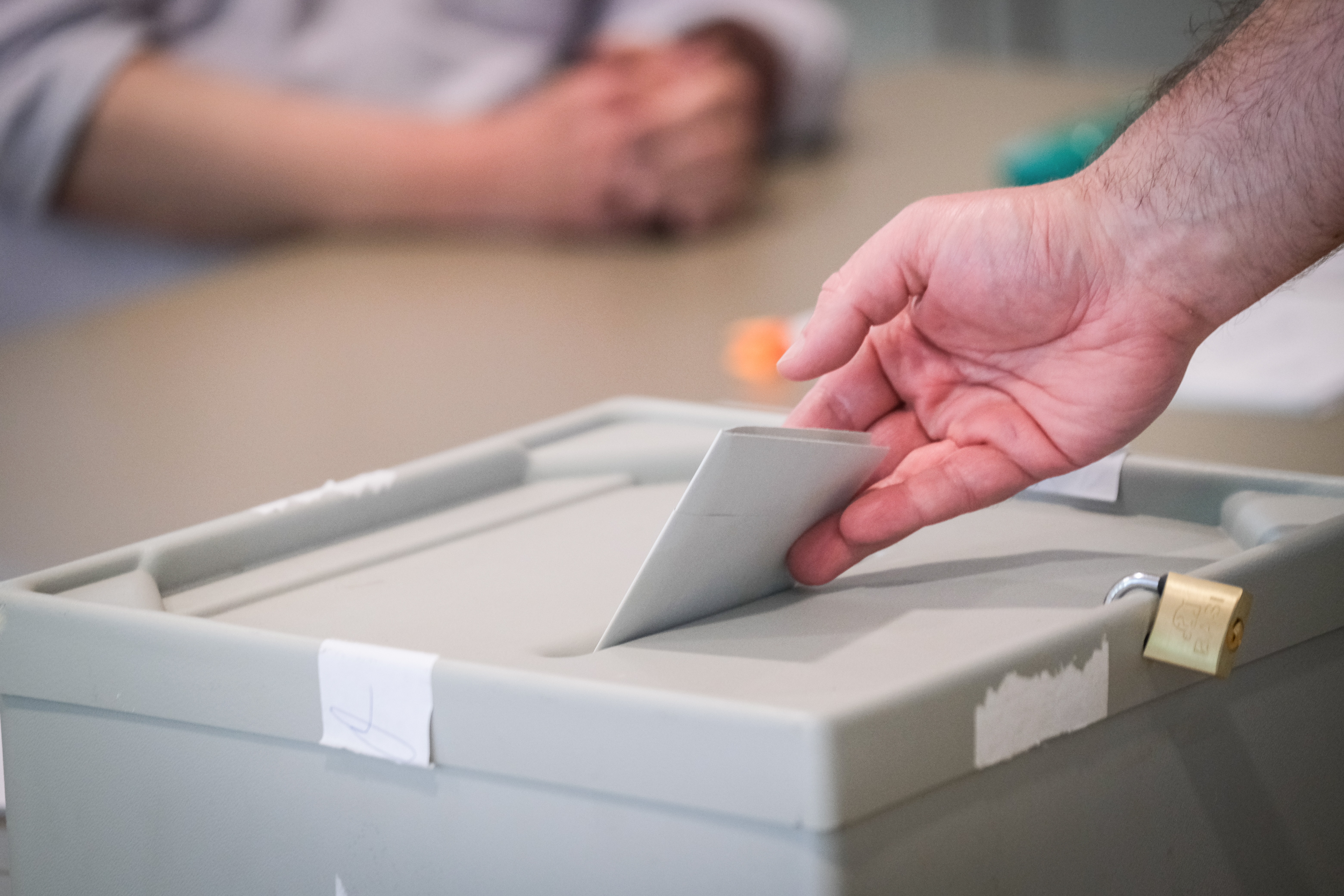 Wahlzettel wird in eine Wahlurne geworfen